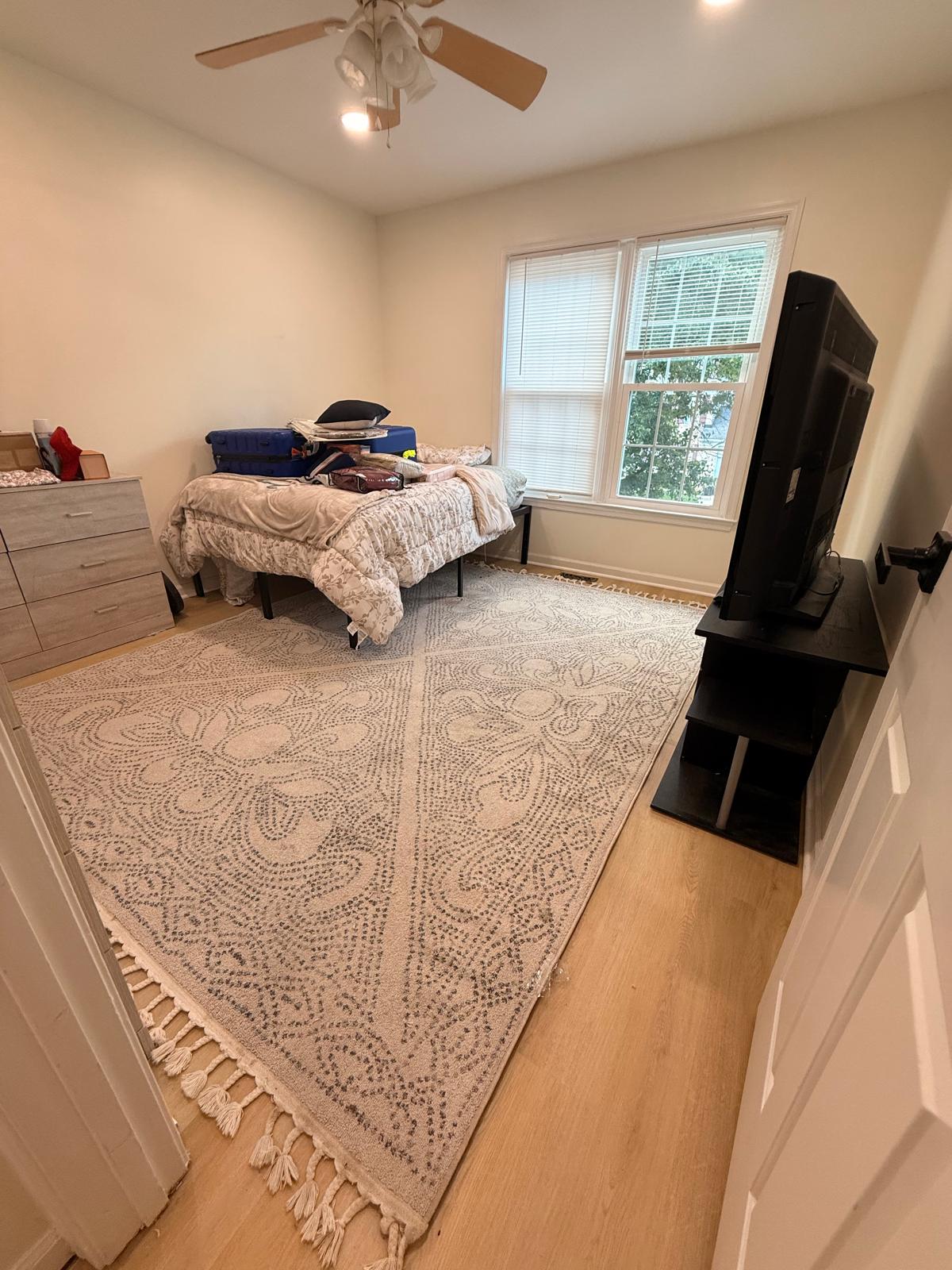 Finished bedroom with new light plank flooring, fresh baseboards, painted walls and window trim