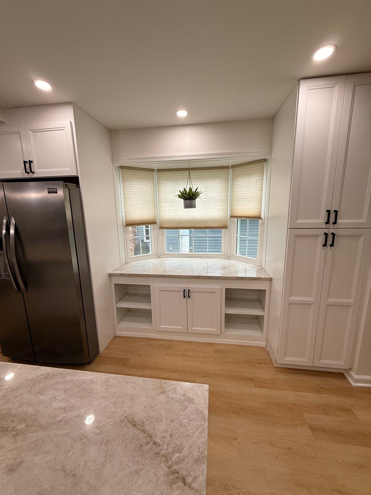 Finished kitchen with full-height white pantry cabinets, a built-in refrigerator enclosure and recessed ceiling lights
