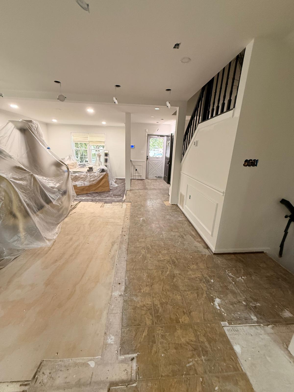 Entry hallway and staircase with flooring removed and fixture wiring hung ready for new lights