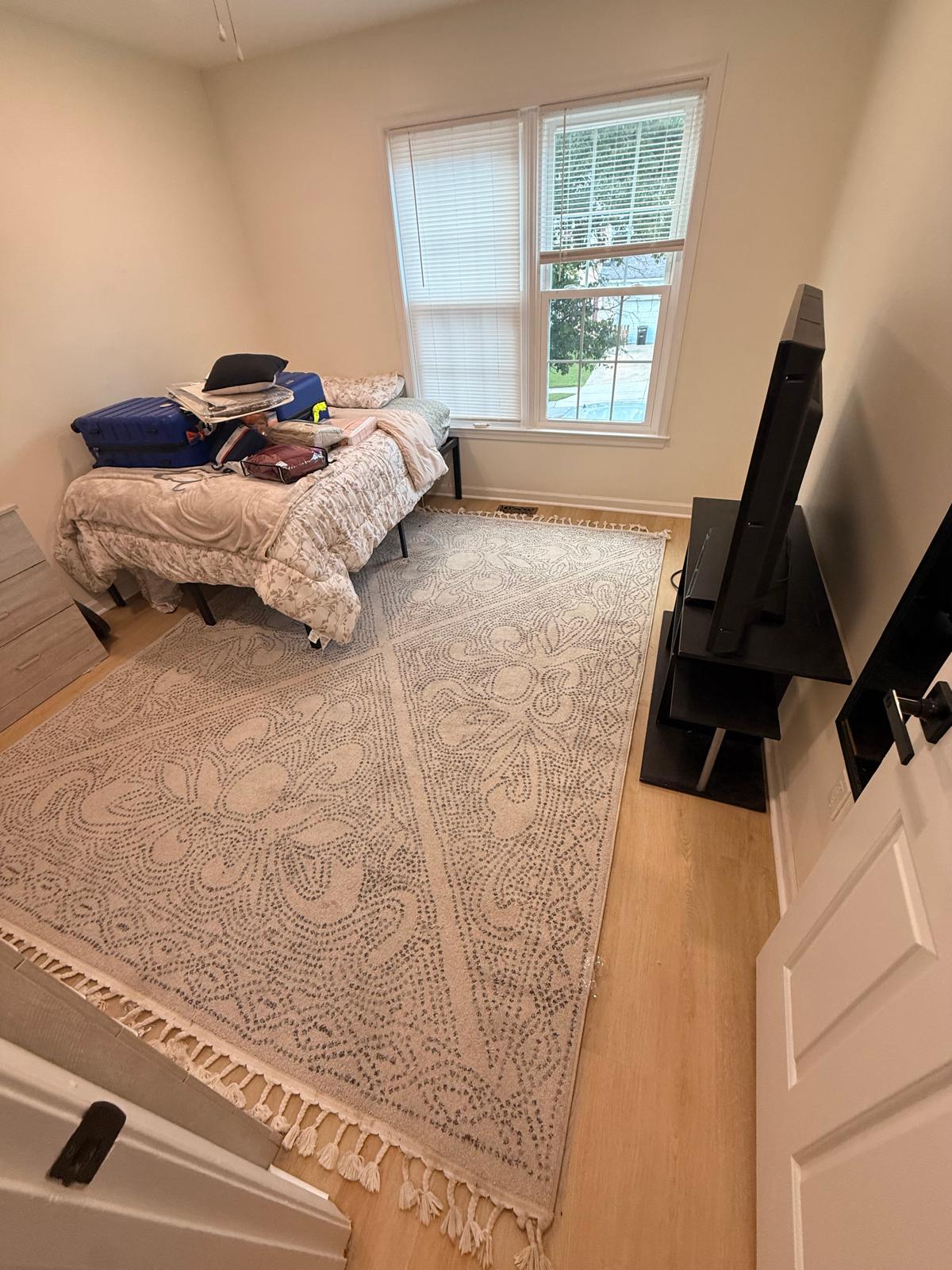 Finished bedroom showing new plank flooring under an area rug, painted walls and ceiling fan