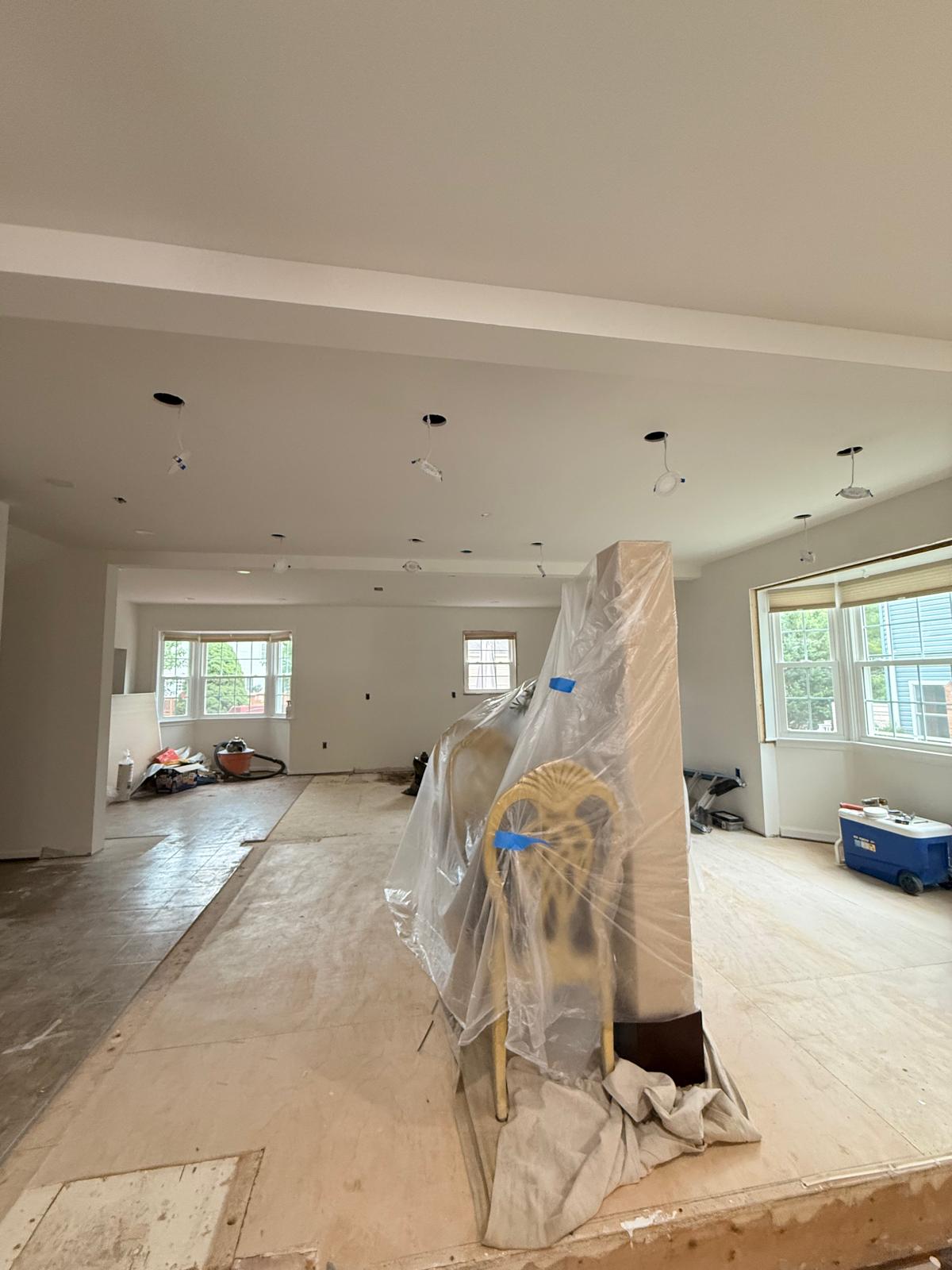 Open living and dining space facing the rear windows with ceiling openings cut for recessed lighting