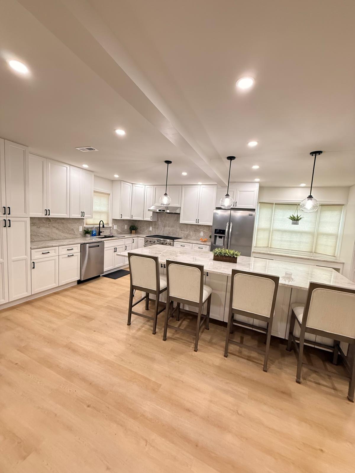 Elevated wide-angle view of a finished open-plan kitchen with a large island, stone backsplash and light wide-plank flooring