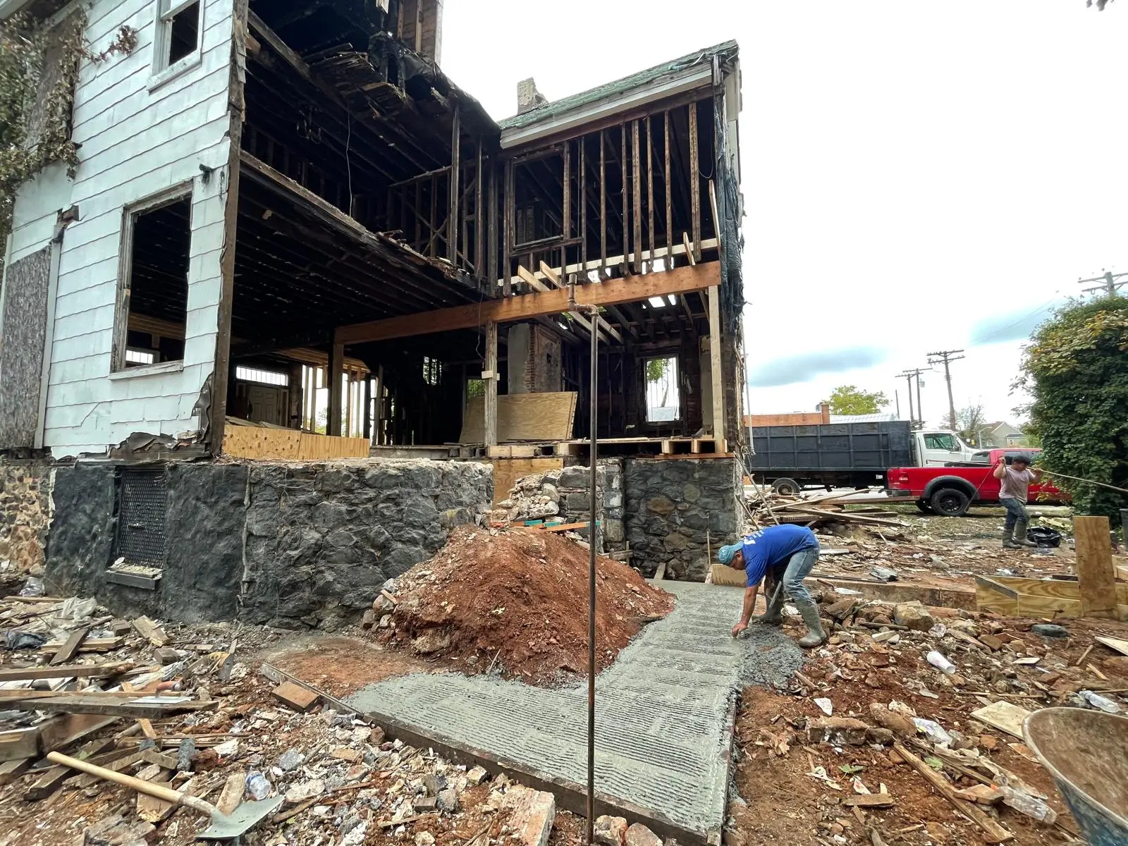 Home mid-remodel with exposed framing, new structural beam, and fresh concrete walkway