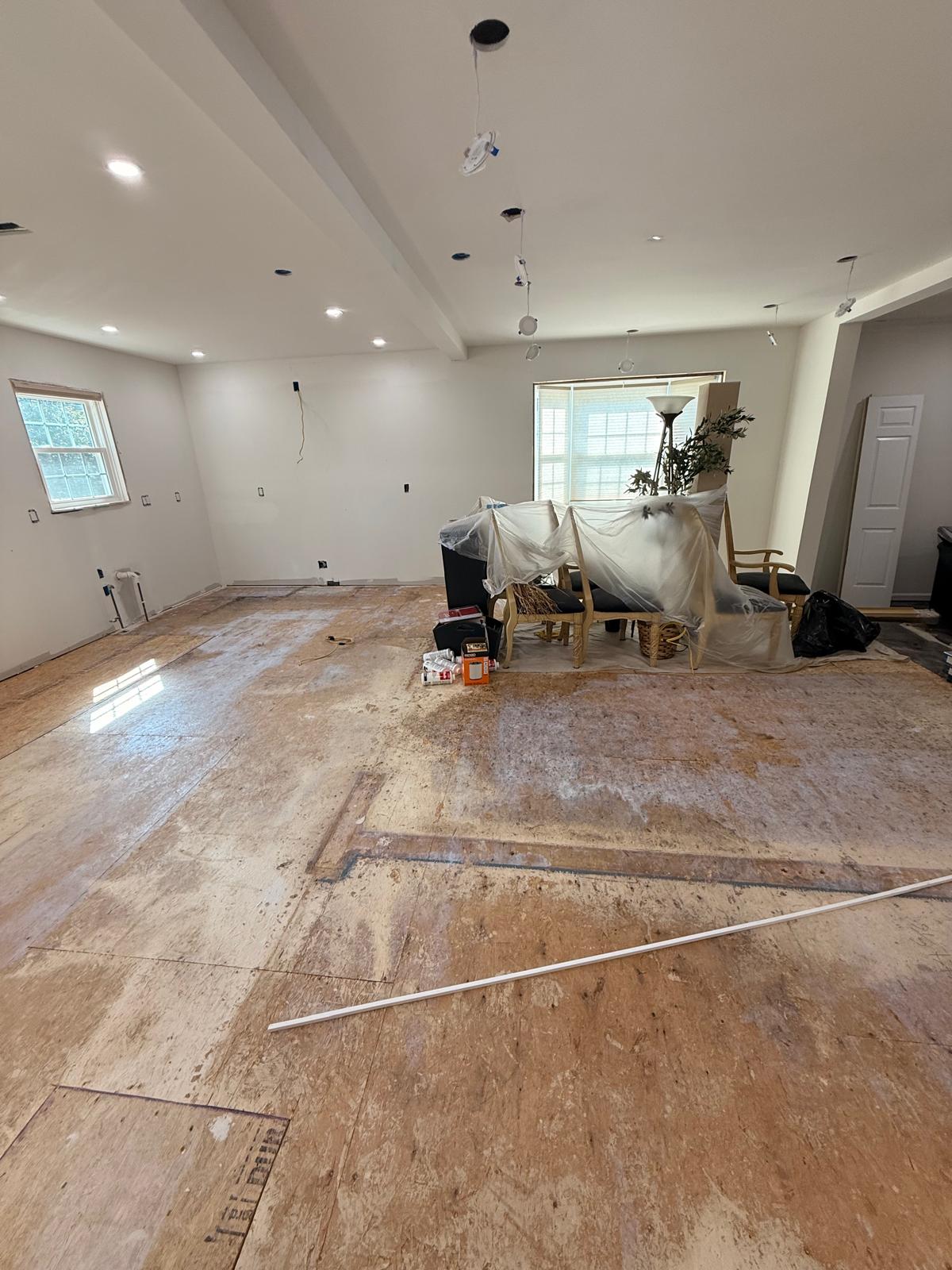 Kitchen and dining wall with sink plumbing pipes set, open electrical boxes and patched subfloor
