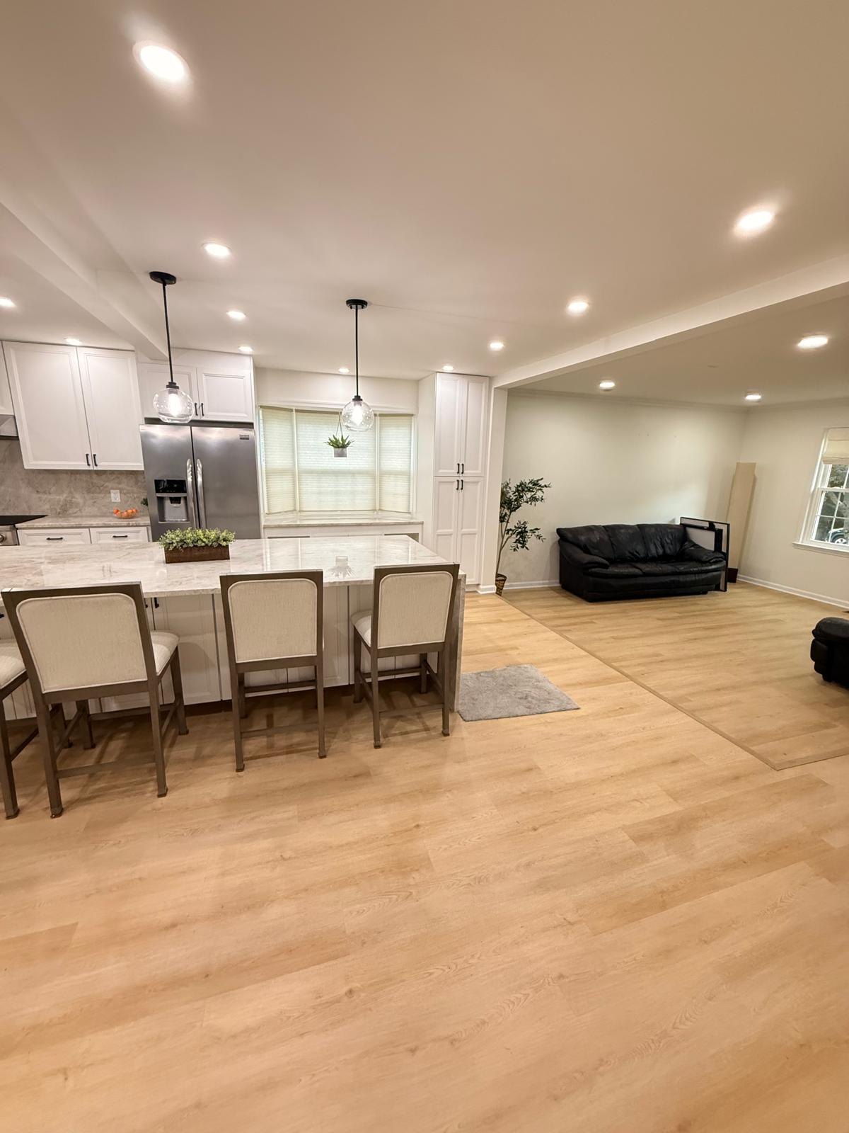 Finished kitchen island with a stone countertop opening into an adjoining living room with light wood-look flooring throughout