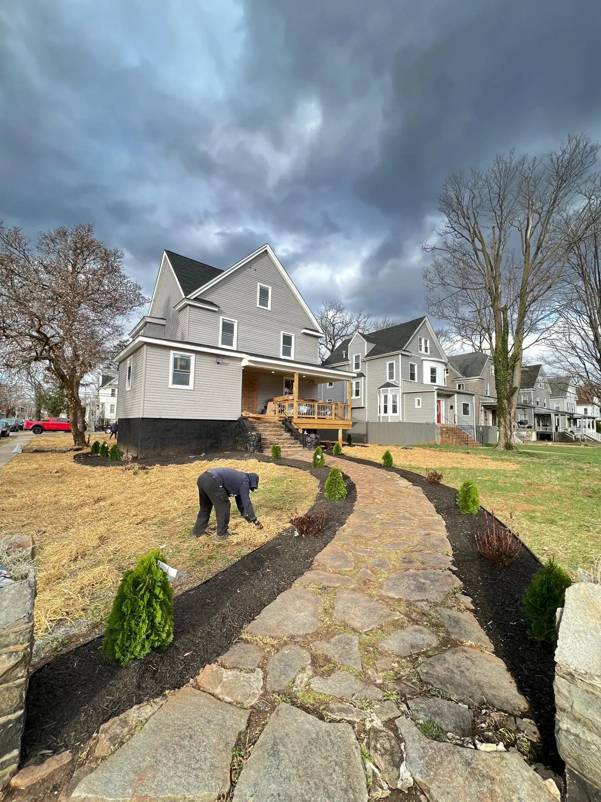 Completed home remodel with new siding, windows, wooden porch, and flagstone walkway