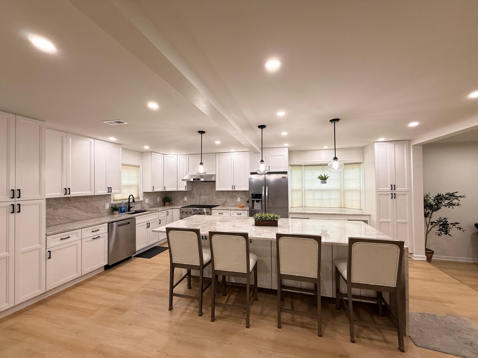 Finished kitchen with white shaker cabinets, tall pantry towers, chimney range hood, French-door refrigerator and a bay-window bench