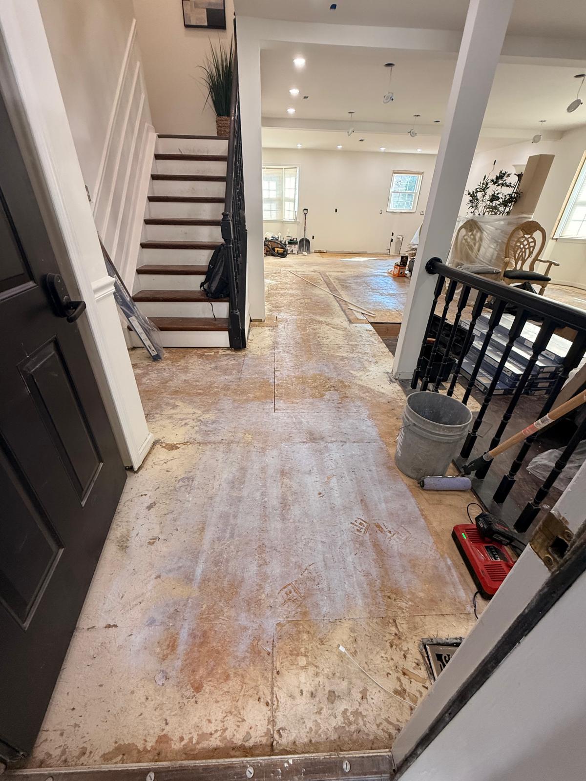 Front foyer and hall with subfloor scraped clean and boxes of new flooring stacked ready for install